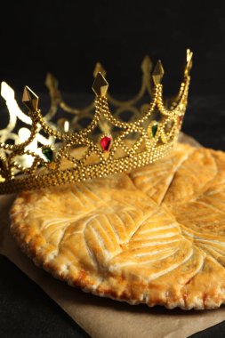 Geleneksel galette des Rois siyah masa üzerinde dekoratif taç, yakın plan