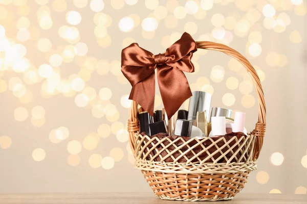 Wicker basket with cosmetics as present against blurred festive lights. Space for text