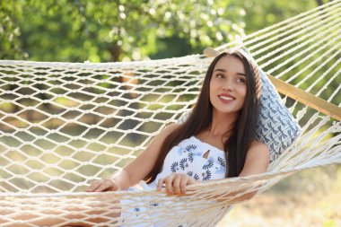 Genç bayan yeşil bahçedeki hamakta dinleniyor.