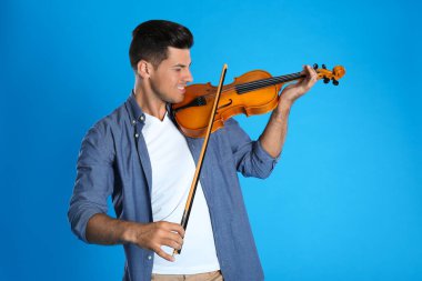 Açık mavi arka planda keman çalan mutlu adam