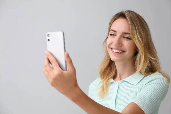 Jovem Mulher Desbloqueando Smartphone Com Scanner Facial Fundo Cinza Verificação — Fotografia de Stock