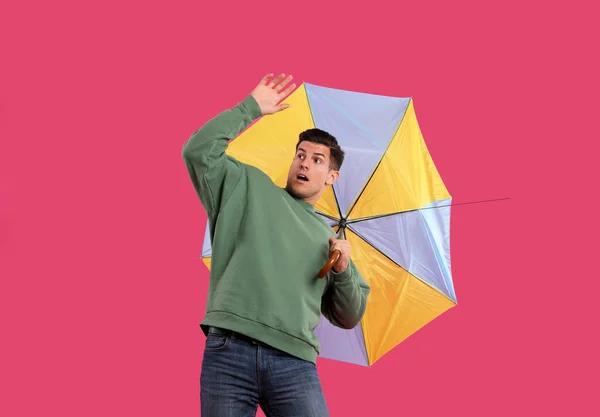 Emocionální Muž Deštníkem Chycený Poryvu Větru Růžovém Pozadí — Stock fotografie