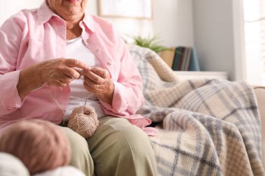 Evde örgü ören yaşlı bir kadın, yakın çekim. Yaratıcı hobi