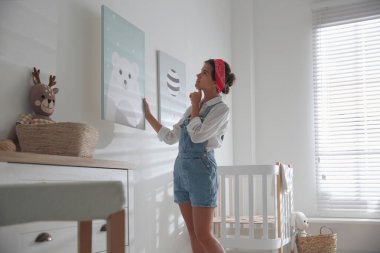 Bebek odasındaki beyaz duvara resim asan bir dekoratör. İç tasarım