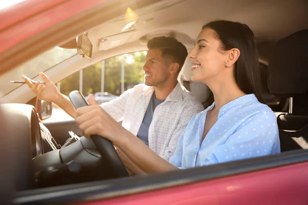 Young woman and instructor in car outdoors. Driving school