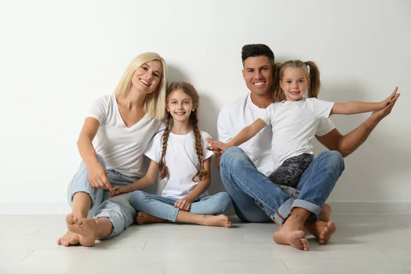 Família Feliz Sentado Chão Perto Parede Branca — Fotografia de Stock