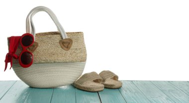 Açık mavi ahşap masada plaj aksesuarları olan şık bir çanta. Metin için boşluk