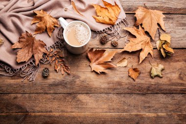 Düz kompozisyon, bir fincan sıcak içecek ve sonbahar yaprakları ile ahşap masa üzerinde, metin için boşluk. Sıcak atmosfer