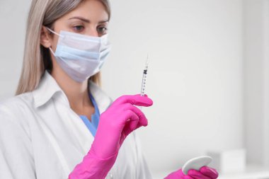 Doktor elinde şırıngayla aşıyı hastanede tutuyor.