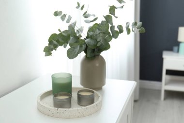 Mumlar ve okaliptüs dalları beyaz masa içinde. İç öge