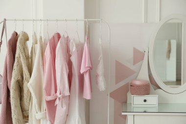 Giysi askısı ve yuvarlak aynalı bir soyunma odası.