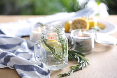 Limonlu mason kavanozu, taze biberiye ve ahşap masada su. Doğal ev yapımı itici.
