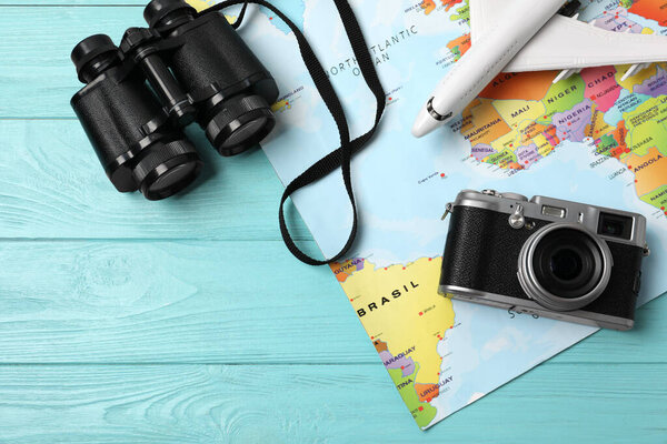 Flat lay composition with world map and different travel accessories on turquoise wooden table. Planning summer vacation trip