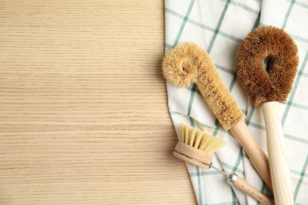 Cleaning brushes on wooden table, flat lay and space for text. Dish washing supplies