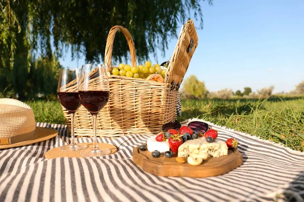 Red wine and different products for summer picnic served on blanket outdoors