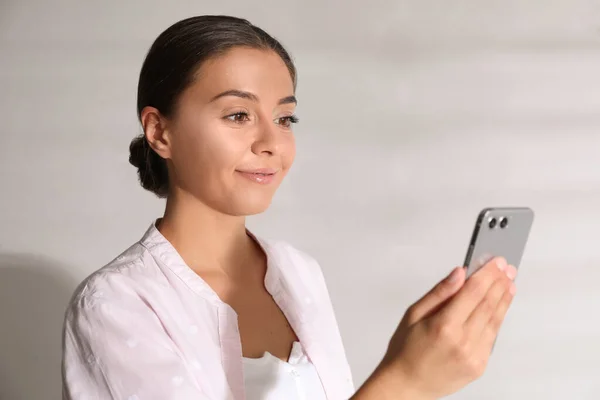 Jovem Mulher Desbloqueando Smartphone Com Scanner Facial Perto Parede Branca — Fotografia de Stock