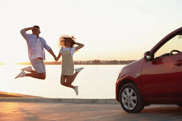 Glückliches Paar Springt Bei Sonnenuntergang Der Nähe Von Autos Freien — Stockfoto