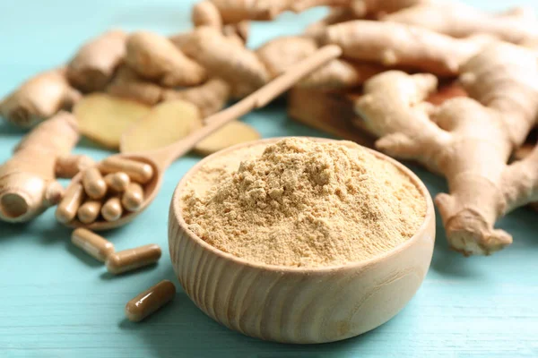 Kuru, kapsüllü ve açık mavi ahşap masada taze zencefil, yakın plan.