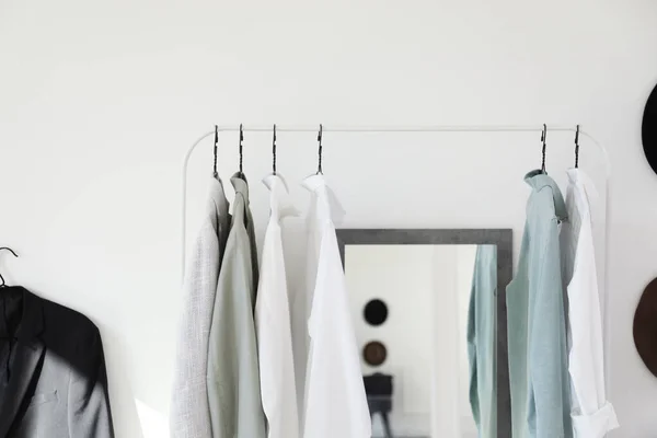 Rack with stylish clothes near mirror in dressing room