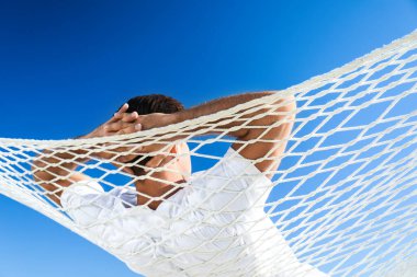 Güneşli bir günde hamakta dinlenen bir adam. Yaz tatili