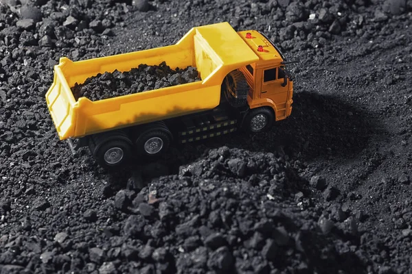 Toy tipper truck with coal in field