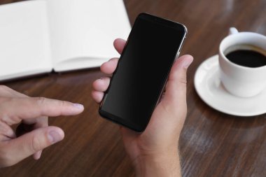 Kafedeki masada akıllı telefonu olan adam, yakın plan.