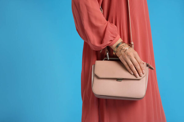 Young woman with stylish pink bag on light blue background, closeup. Space for text