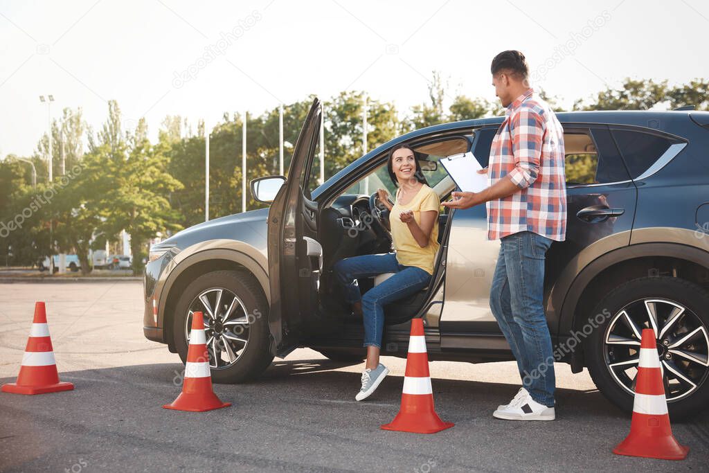 Instructor with clipboard and his student near car outdoors. Driving school exam