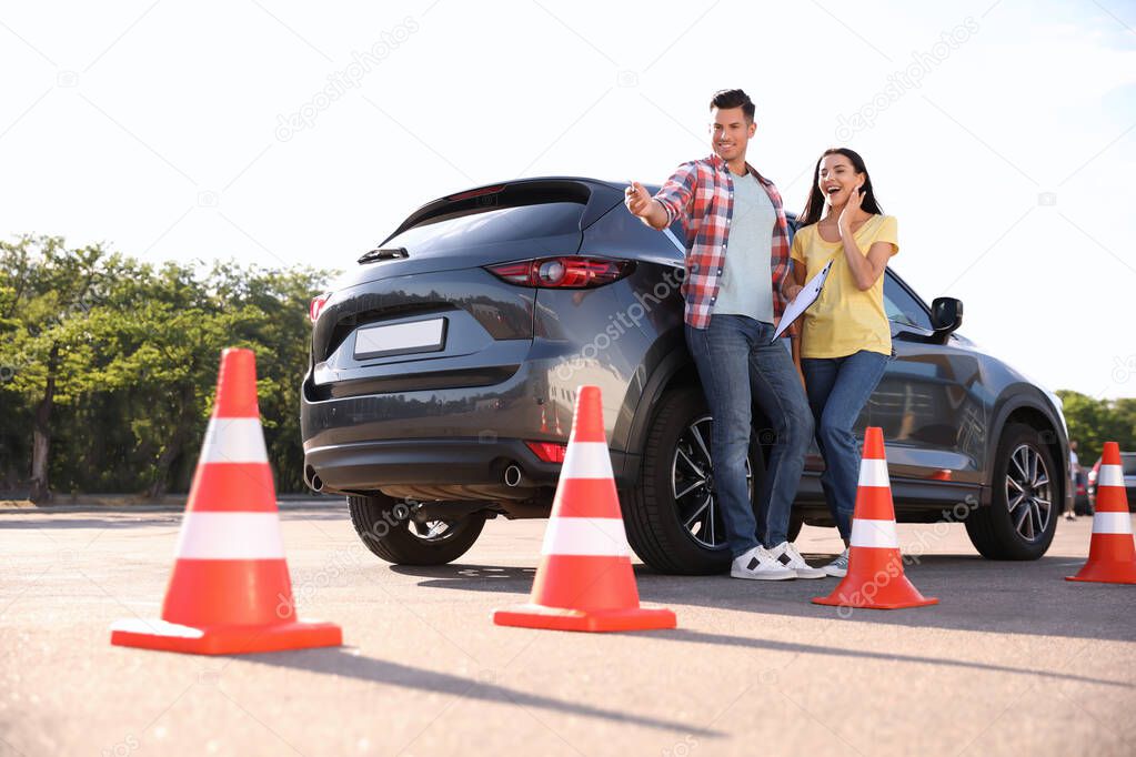 Instructor with clipboard and his student near car outdoors. Driving school exam