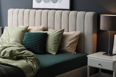 Modern oda içinde yeni şam fıstıklı çarşafları olan rahat bir yatak.