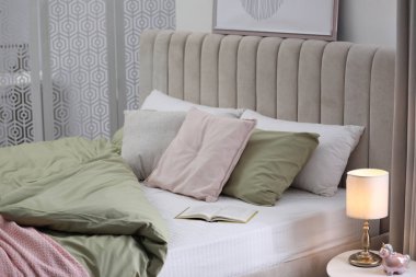 Modern oda içinde yeni şam fıstıklı çarşafları olan rahat bir yatak.