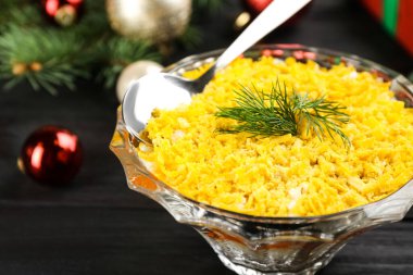 Geleneksel Rus salatası Mimosa ve koyu ahşap masa üzerindeki şenlikli dekor, yakın plan.