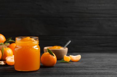 Koyu ahşap masada cam kavanozda lezzetli bir mandalina reçeli. Metin için boşluk