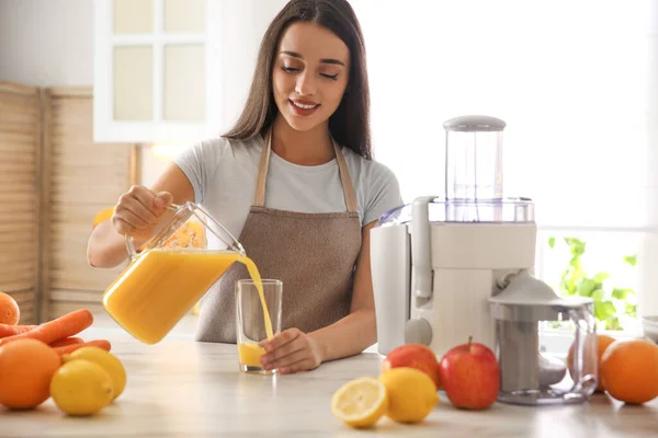 Mujer Joven Vertiendo Sabroso Jugo Fresco Vaso Mesa Cocina — Foto de Stock