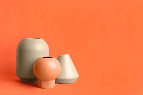 Stylish empty ceramic vases on orange background, space for text