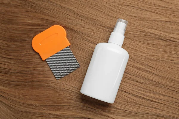 Comb and spray for anti lice treatment on blond hair, flat lay