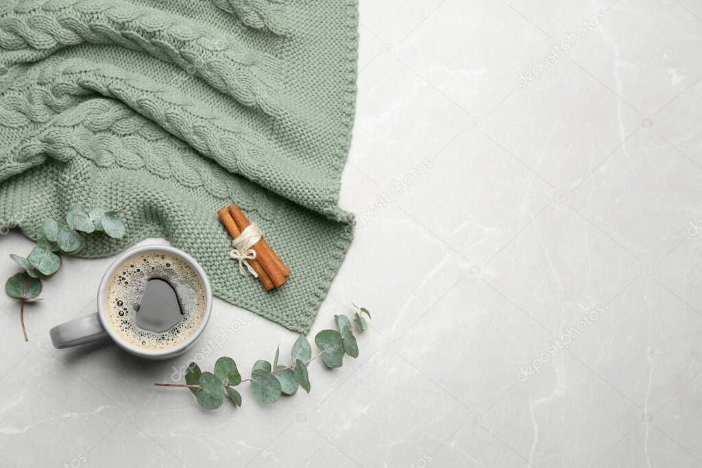 Flat lay composition with hot drink and warm plaid on light marble table, space for text
