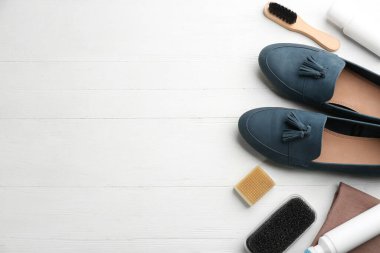 Beyaz ahşap masa üzerinde ayakkabı bakım aksesuarları olan şık ayakkabılar. Metin için boşluk