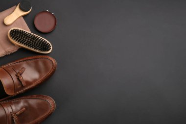 Siyah arka planda ayakkabı bakım aksesuarları ve ayakkabıları olan düz bir kompozisyon. Metin için boşluk