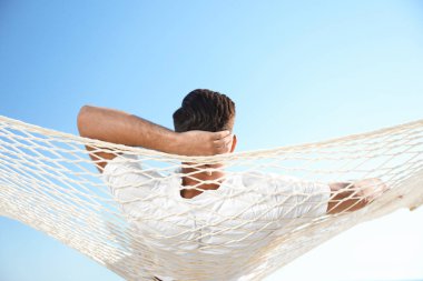 Sahilde hamakta dinlenen bir adam. Yaz tatili