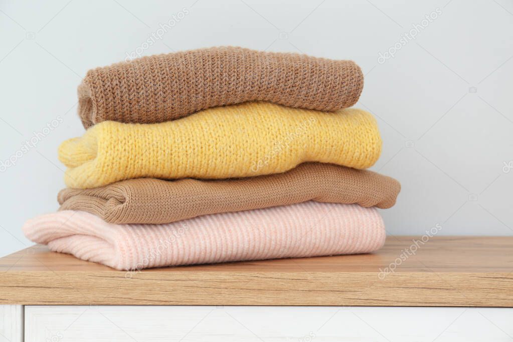 Stack of folded warm knitted sweaters on wooden table