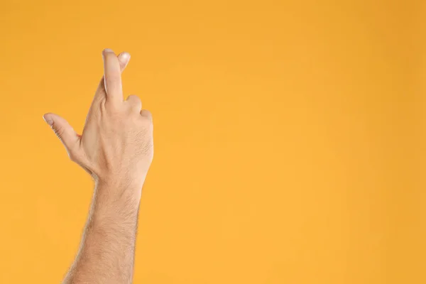 有交叉手指和空间的男人在黄色背景的文字 迷信的概念 — 图库照片