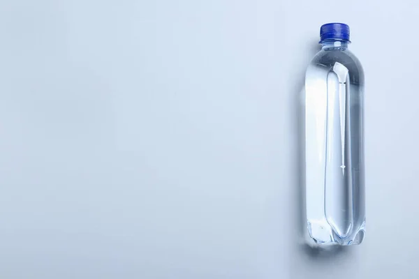 Plastic bottle with water on white background, top view. Space for text