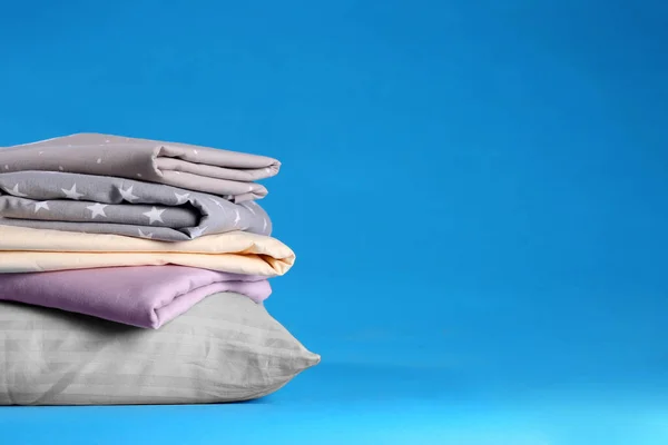 青い背景にきれいなベッドシーツと枕のスタック テキストのスペース — ストック写真