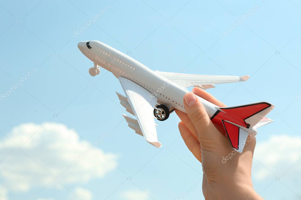 Woman holding toy airplane against blue sky, closeup