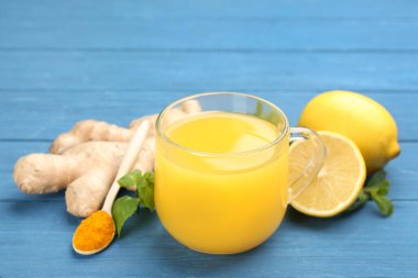 Dokunulmazlık artırıcı içecek ve malzemeler mavi ahşap masada.