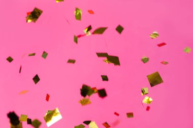 Pembe arka planda parlayan altın konfeti