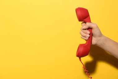 Sarı arka planda kırmızı kablosuz telefonu olan bir kadının yakın çekim görüntüsü, mesaj için boşluk. Yardım hattı kavramı