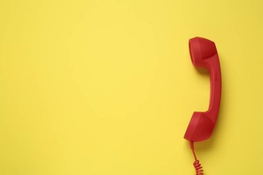 Sarı arka planda kırmızı kablolu telefon, üst manzara. Yardım hattı kavramı