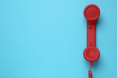 Açık mavi arka planda kırmızı kablolu telefon, üst görüş. Yardım hattı kavramı